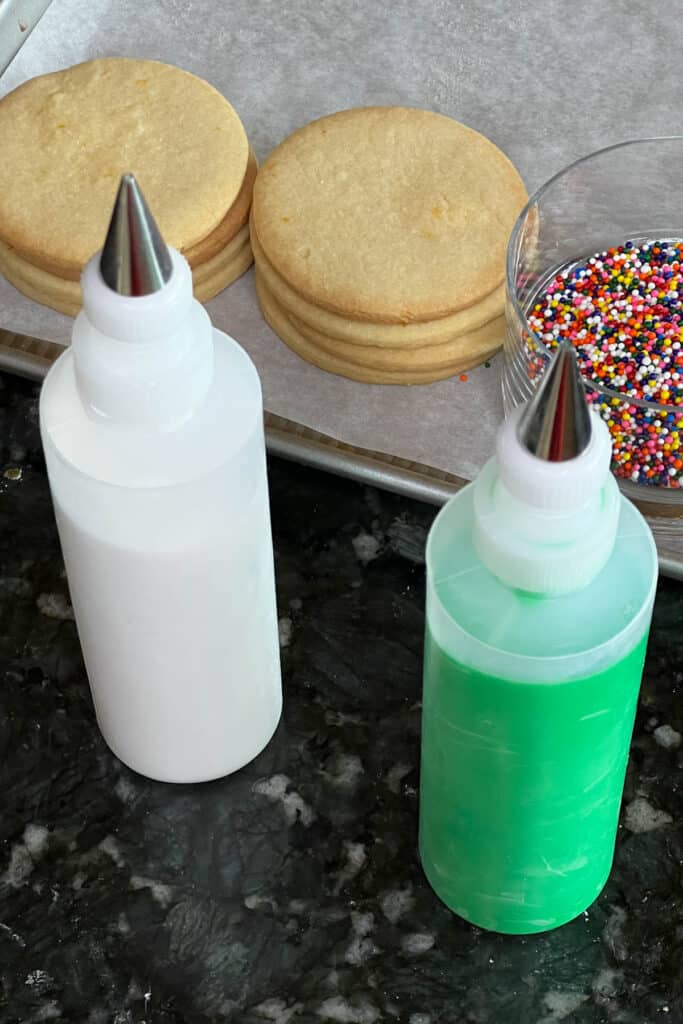 White and green royal icing in squeeze bottles.