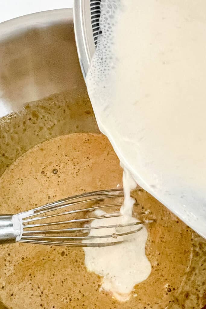 Adding hot cream mixture to the egg mixture to temper it. 