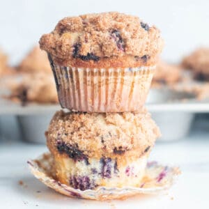 Two blueberry muffins with cinnamon streusel stacked.