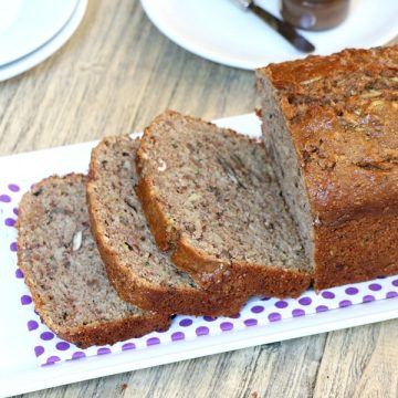 Sliced loaf of spiced apple zucchini bread on a serving plate.