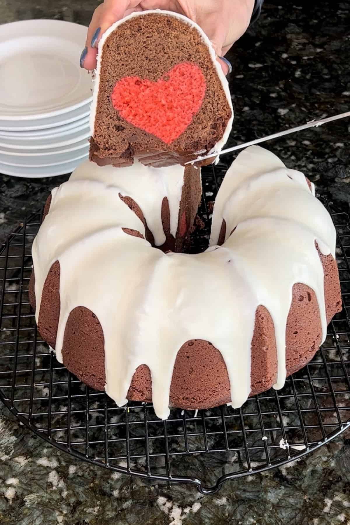 Sliced piece of Chocolate Valentine's Day Bundt Cake in front of the whole cake and white plates