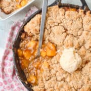 Cast Iron Skillet Peach Cobbler with ice cream on top.