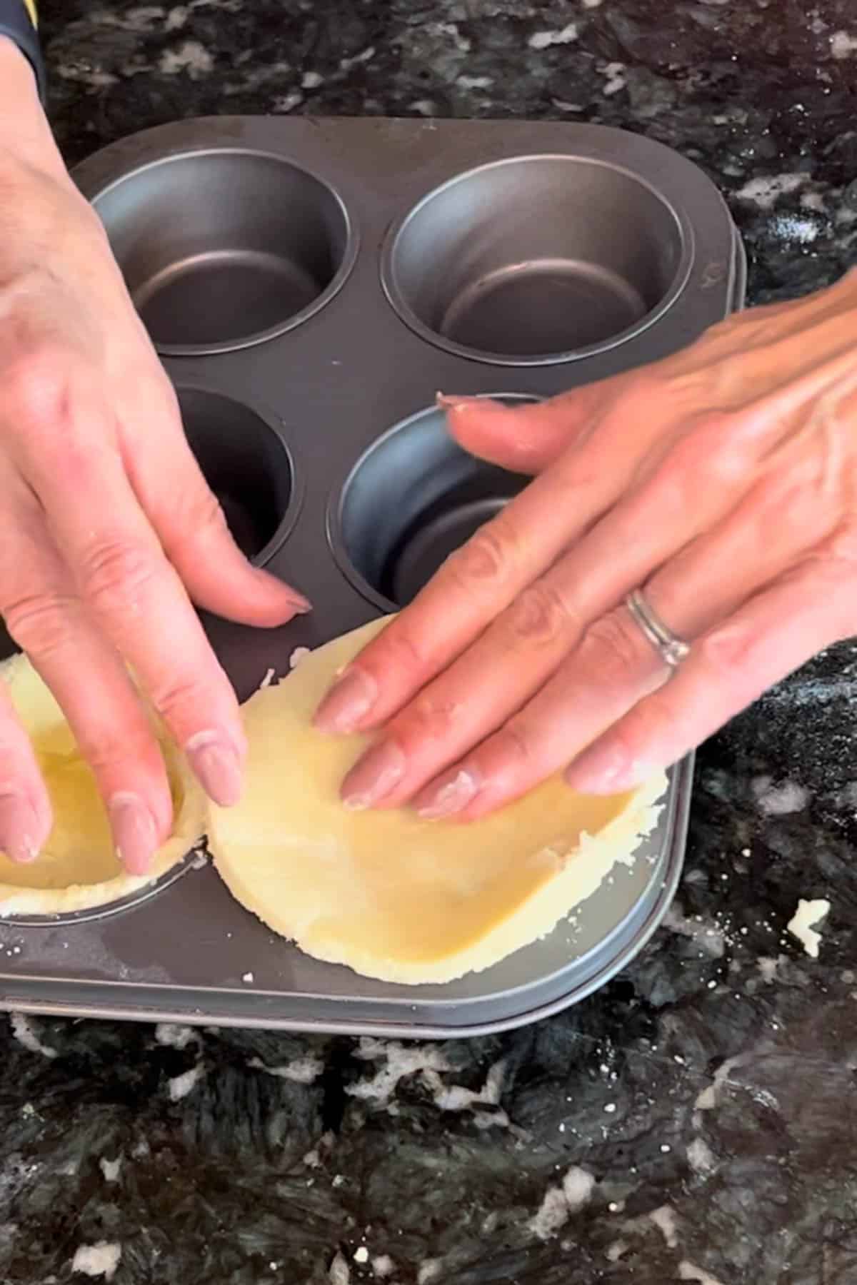 Fitting pie crust rounds into muffin cup tins. 