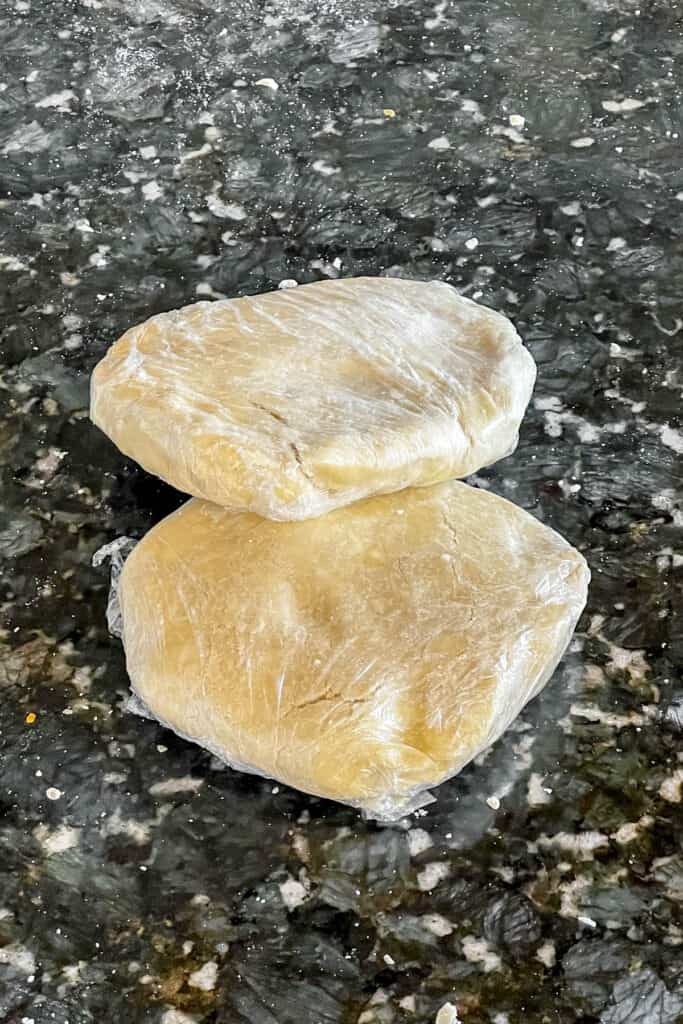 Pie crust dough divided and wrapped in plastic to chill. 