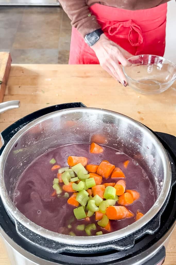 Adding carrots and celery to the pot. 