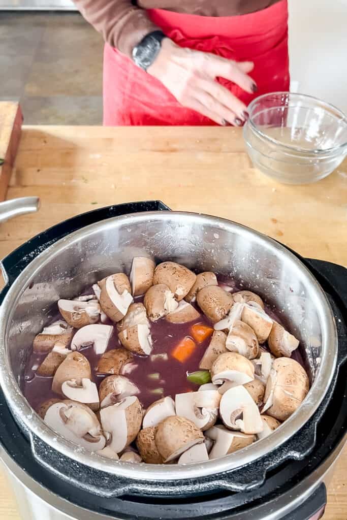 Adding mushrooms to the pot. 