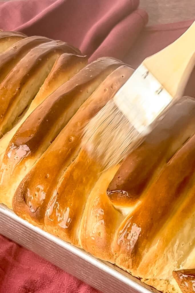 Brushing top of loaf with butter. 