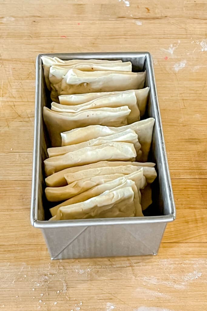 Squares of dough stacked in the bread pan. 