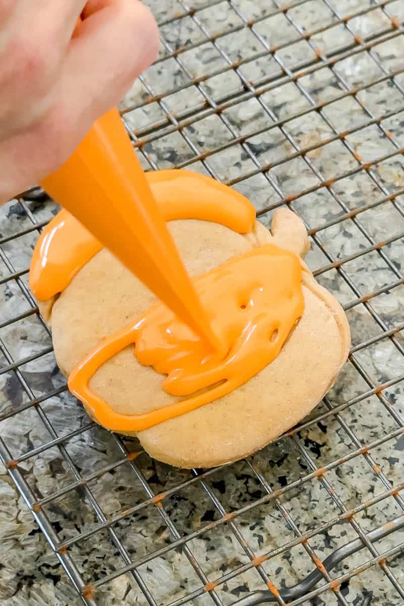 Decorating a pumpkin shaped cookie with royal icing. 